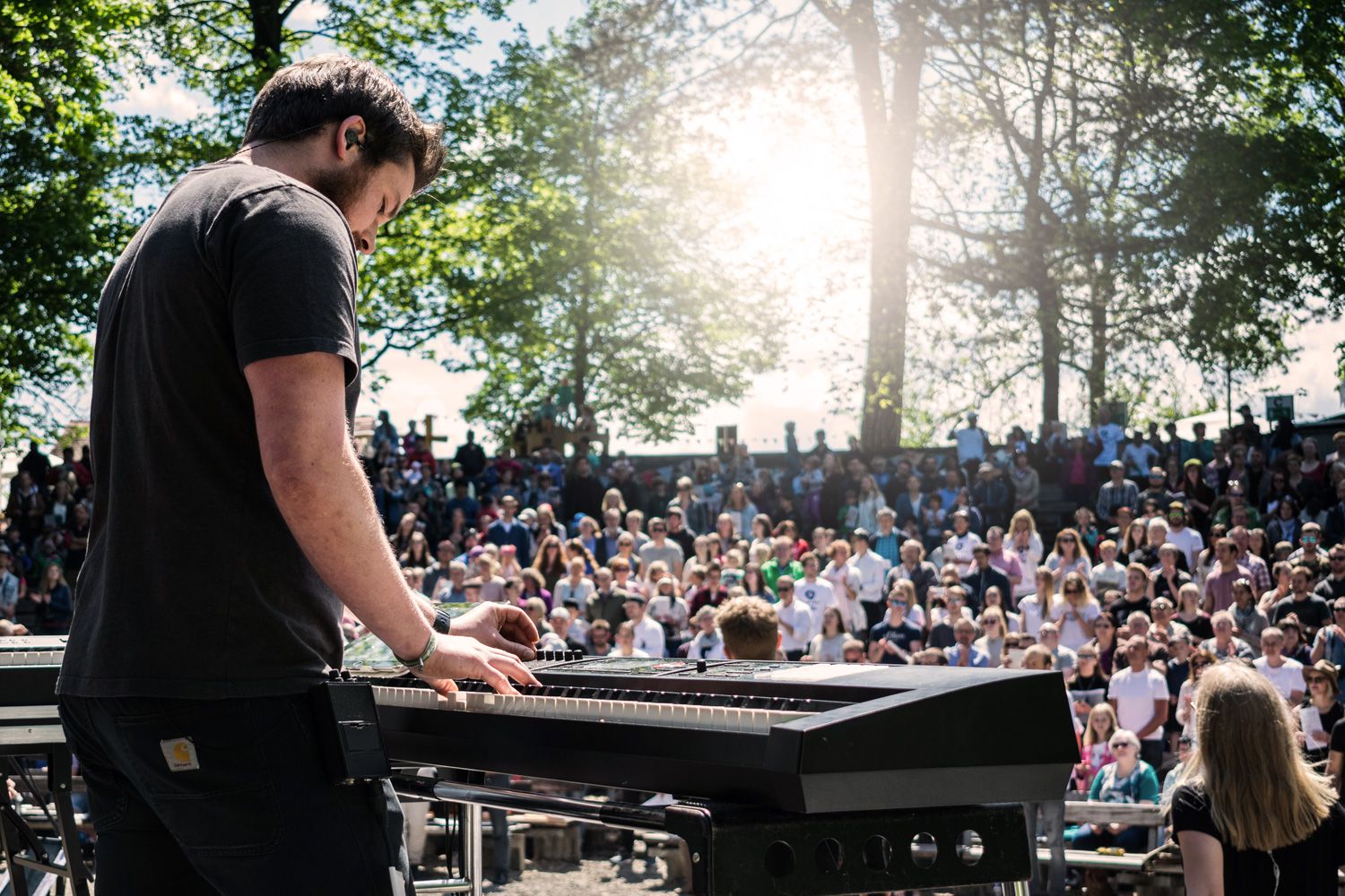 Open-Air-Gottesdienst auf der Burghalde in Kempten: ein Musiker am Klavier vor großem Publikum unter Bäumen