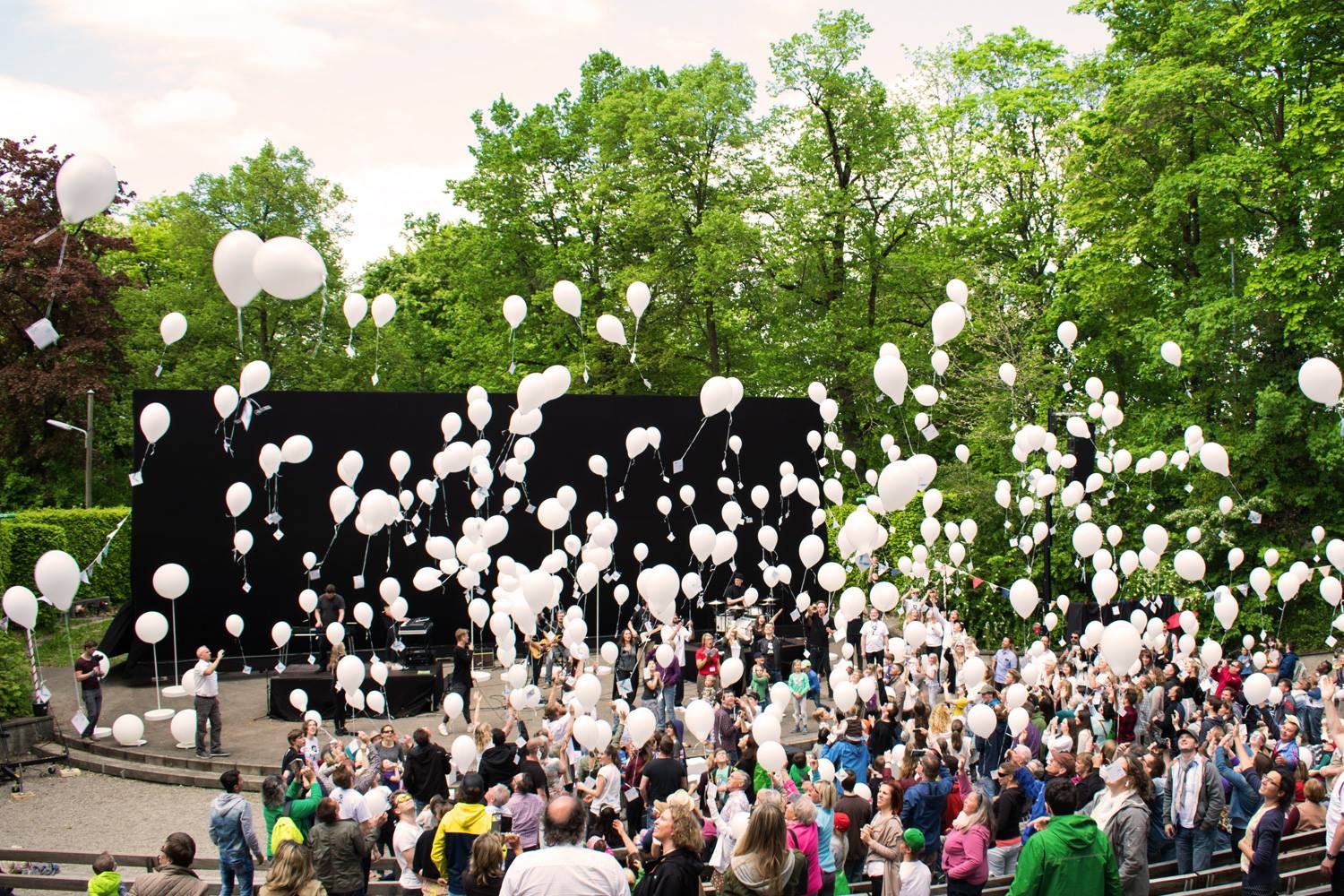 Hunderte weiße Luftballons steigen über der Freilichtbühne auf